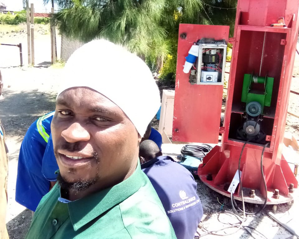 Borehole pump rig mid-install, with the control panel exposed in the foreground.